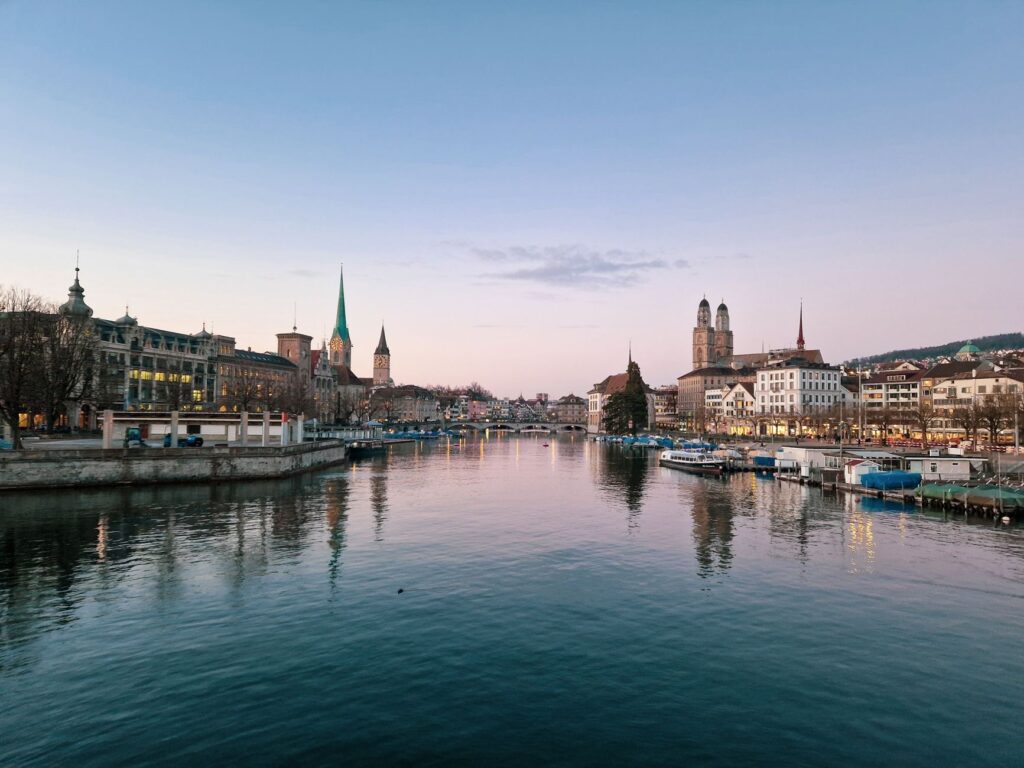 Beautiful evening view of Zürich's skyline with the river reflecting illuminated historic architecture.